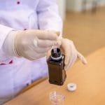 Naukowiec w kombinezonie ochronnym pobiera próbkę cieczy w laboratorium